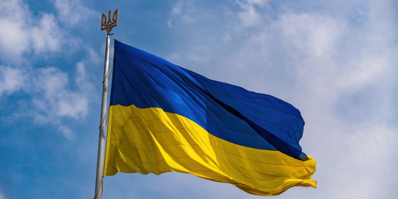 Ukraine Flag - blue and yellow flying in the wind with a blue sky backdrop