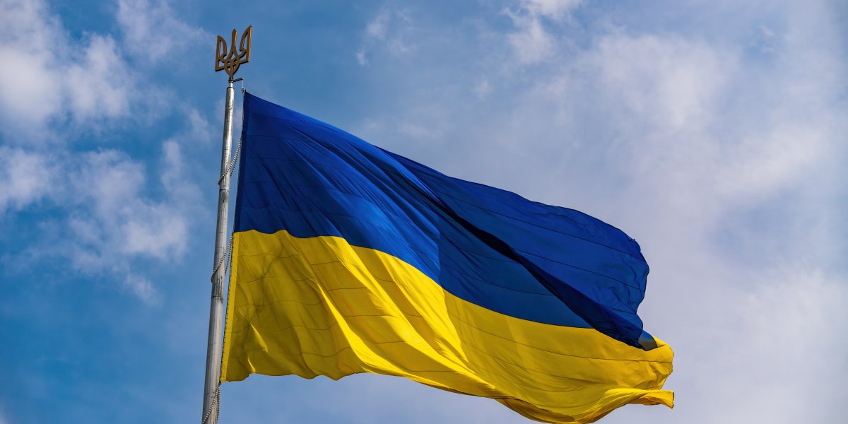 Ukraine Flag - blue and yellow flying in the wind with a blue sky backdrop